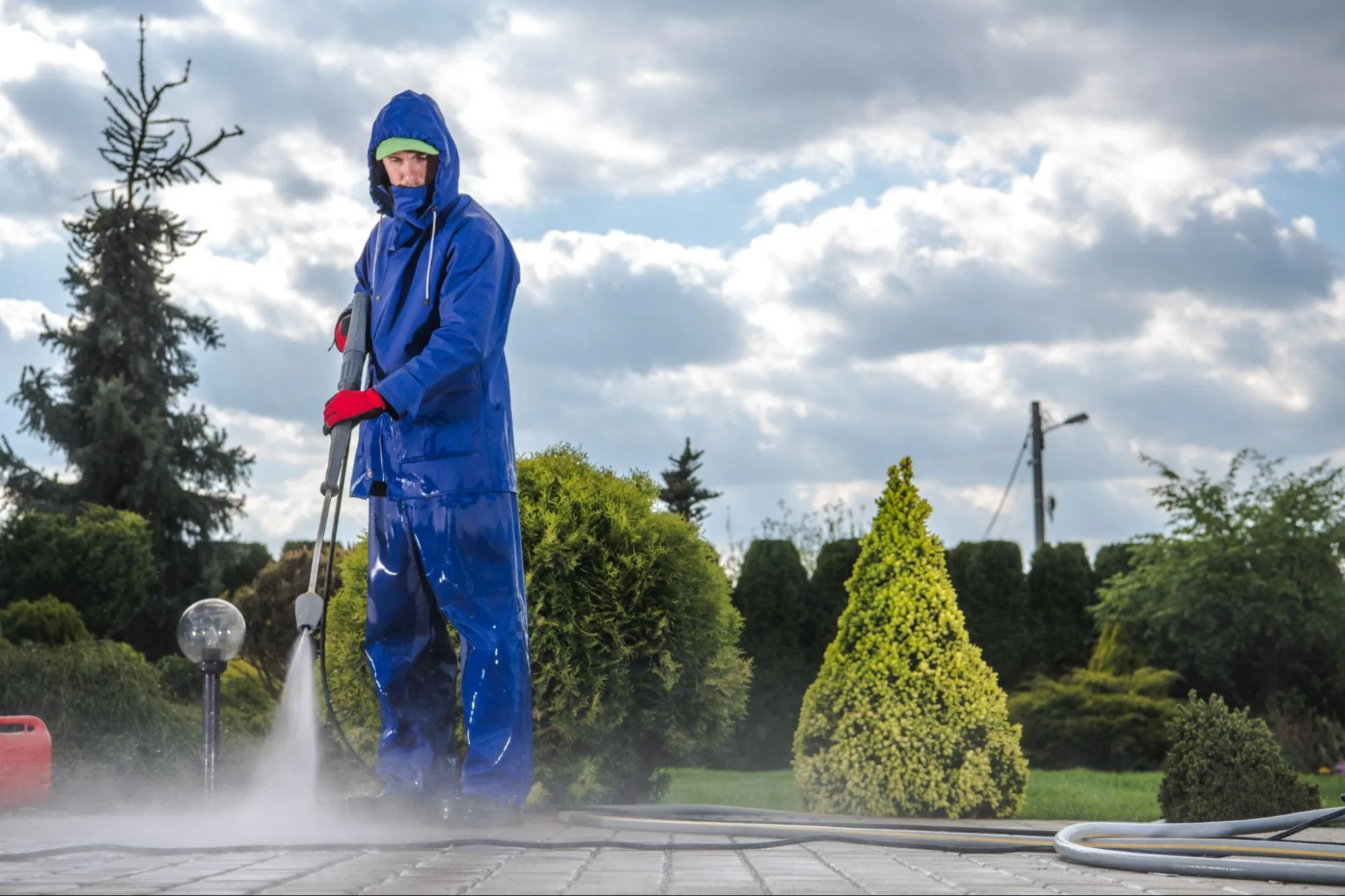 Professional technician pressure washing a concrete patio with high-pressure cleaning gear