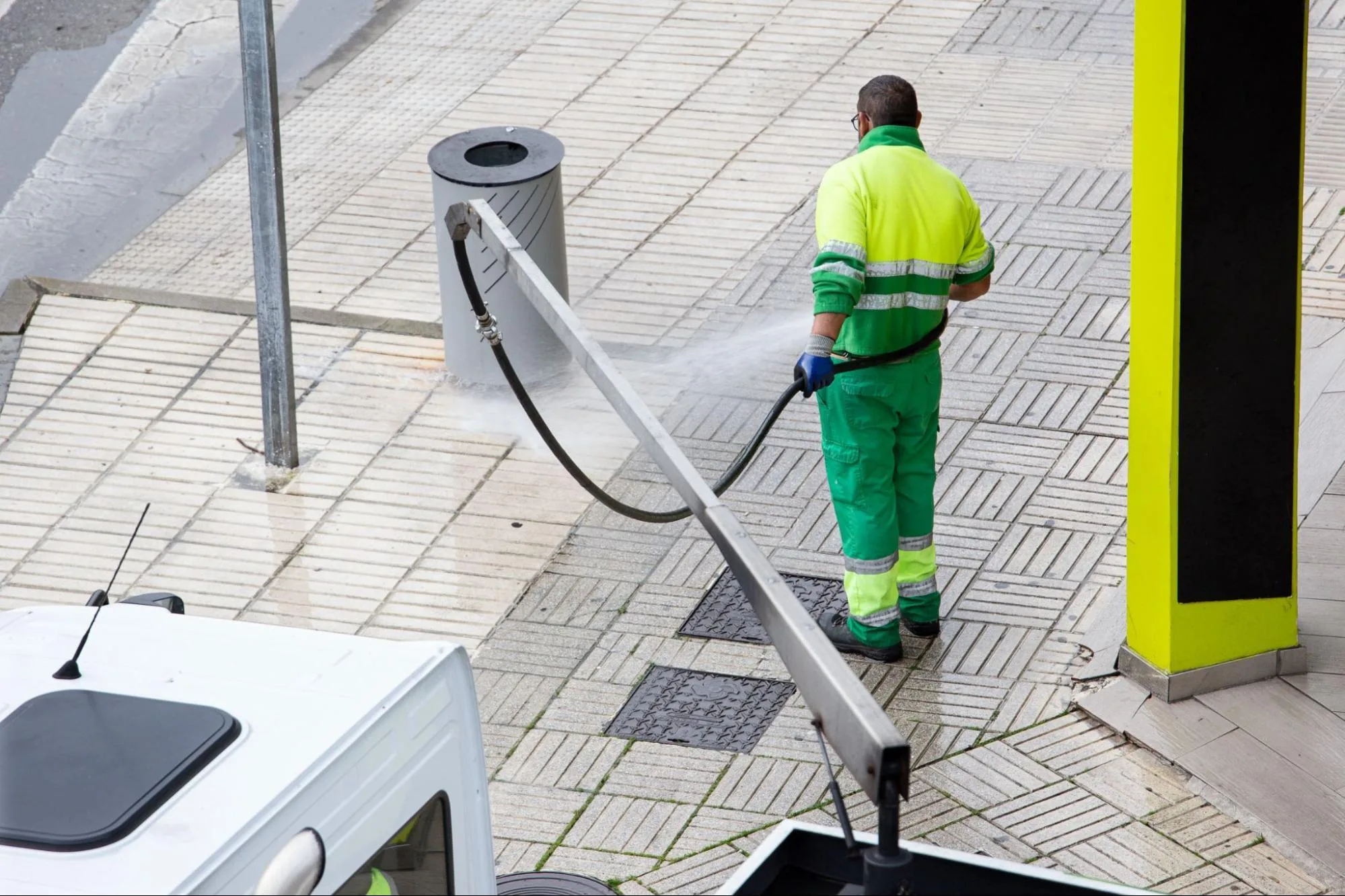 A worker cleans the cargo containers at a port shipyard using an industrial pressure washer