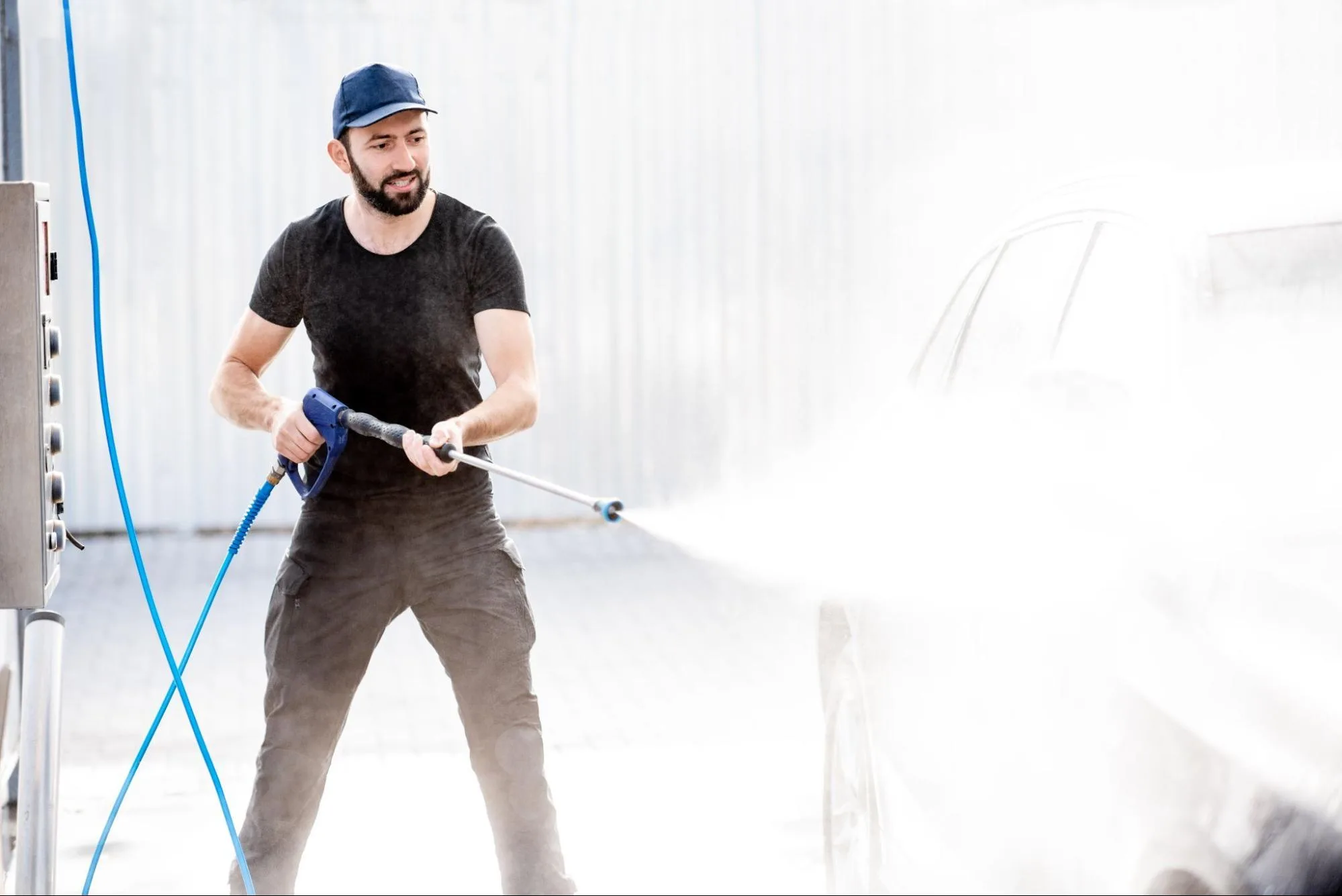 A man washes a car with a pressure washer.