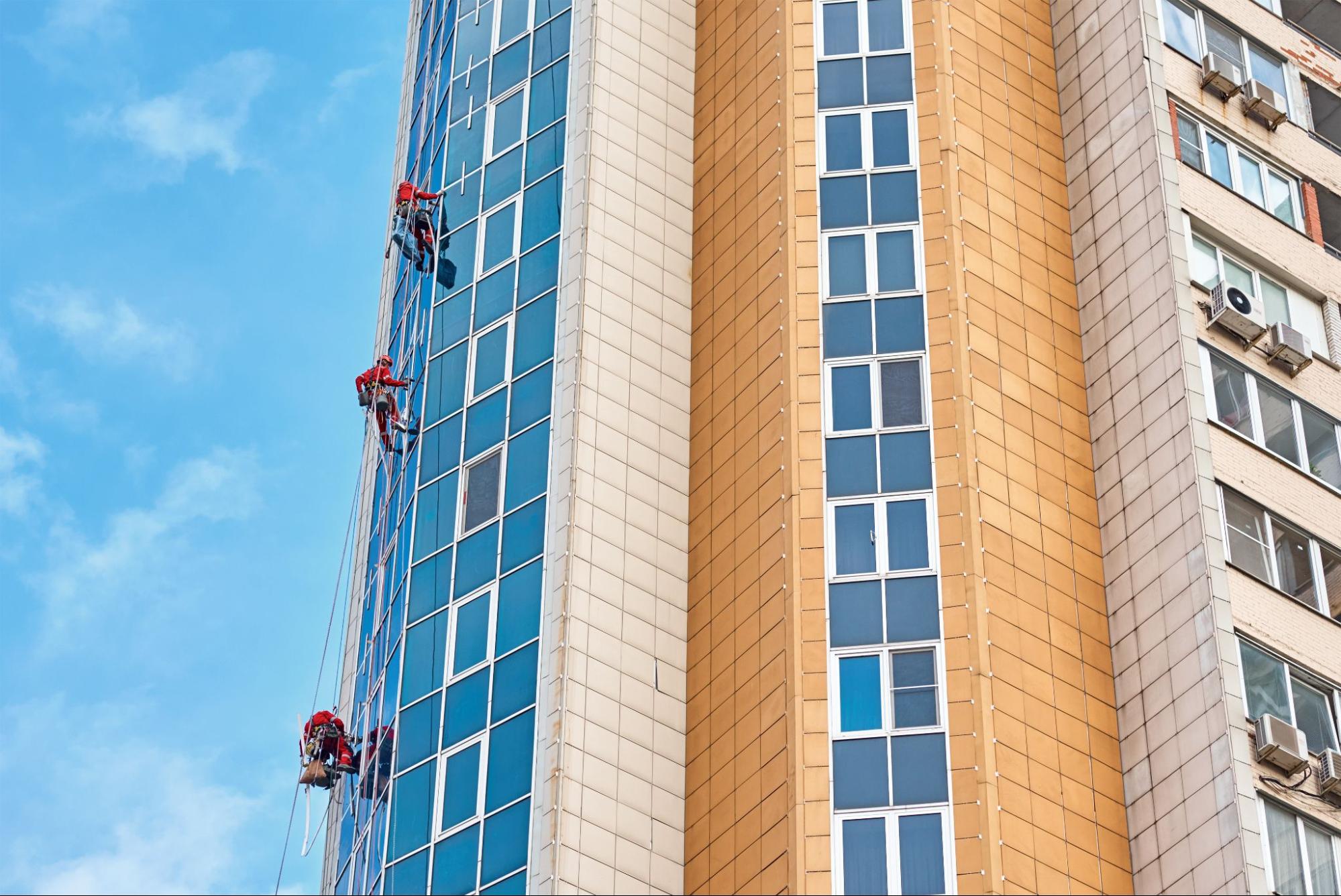 Two workers clean a high-rise window face.