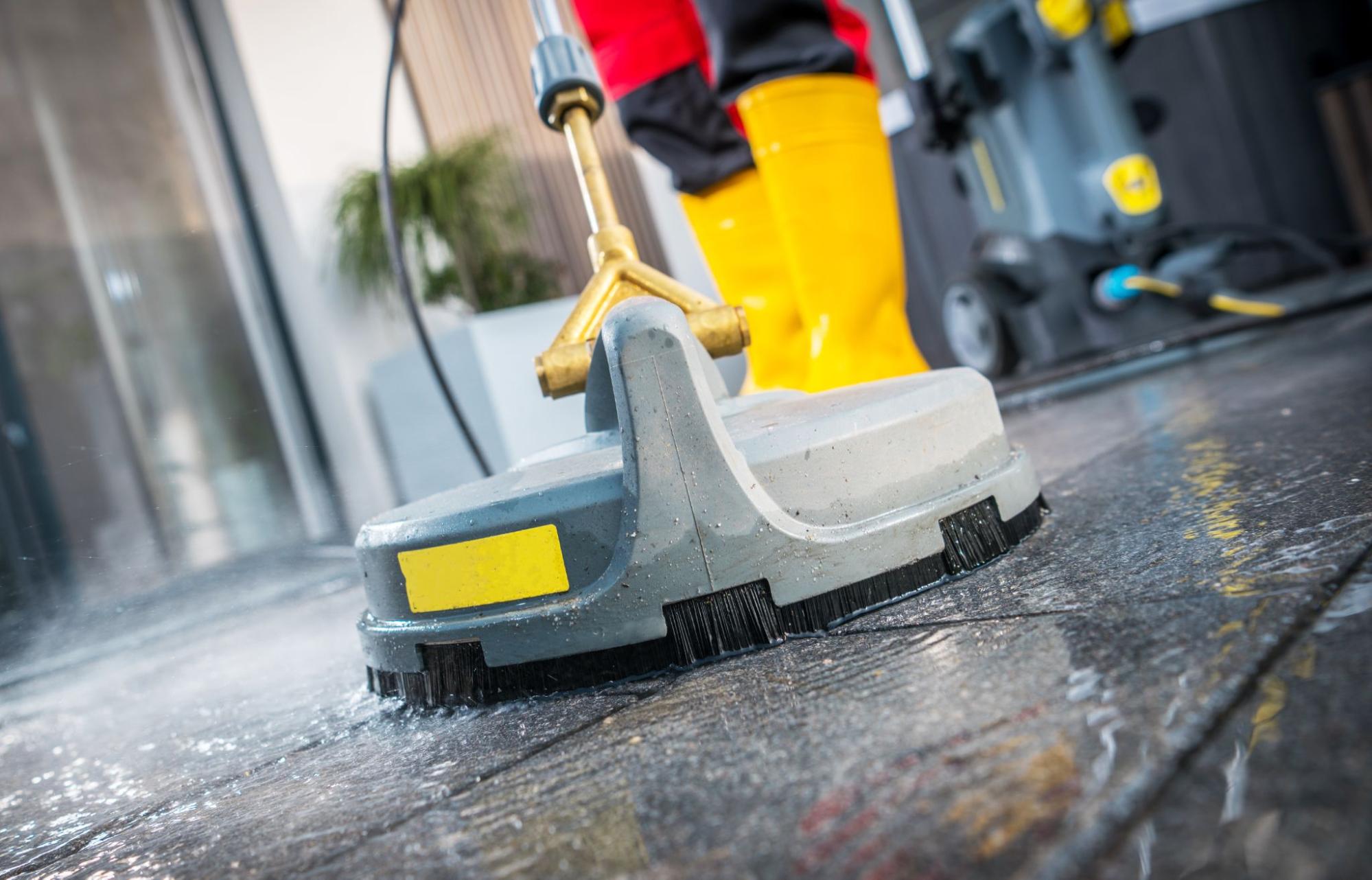 Close-up of a concrete surface cleaner attachment connected to a pressure washer for efficient cleaning