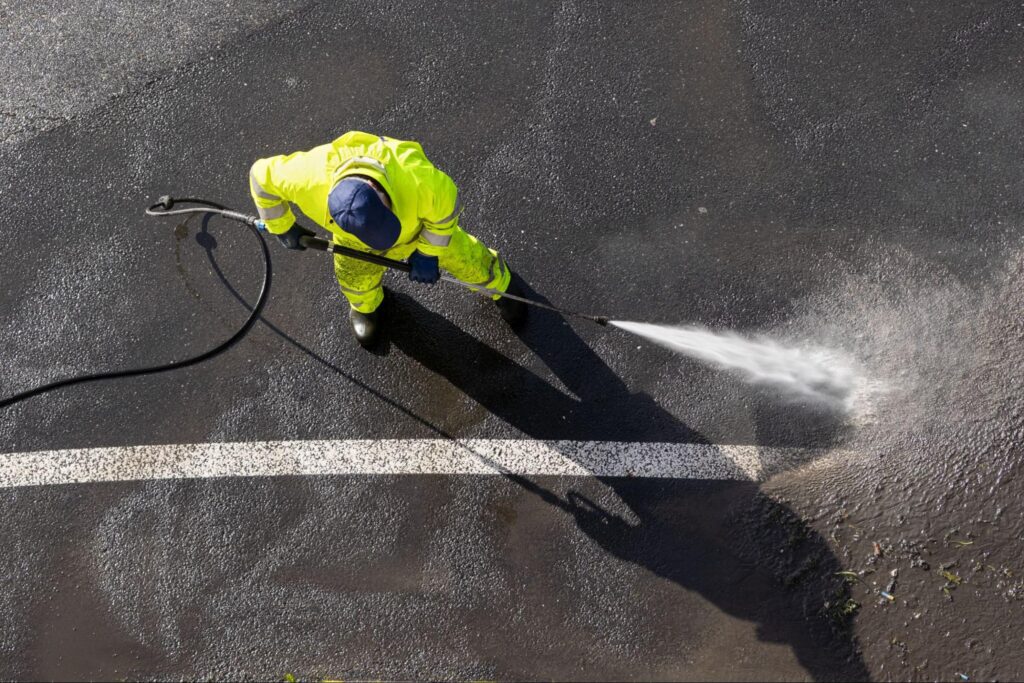 An overview of a worker power washing a parking lot.