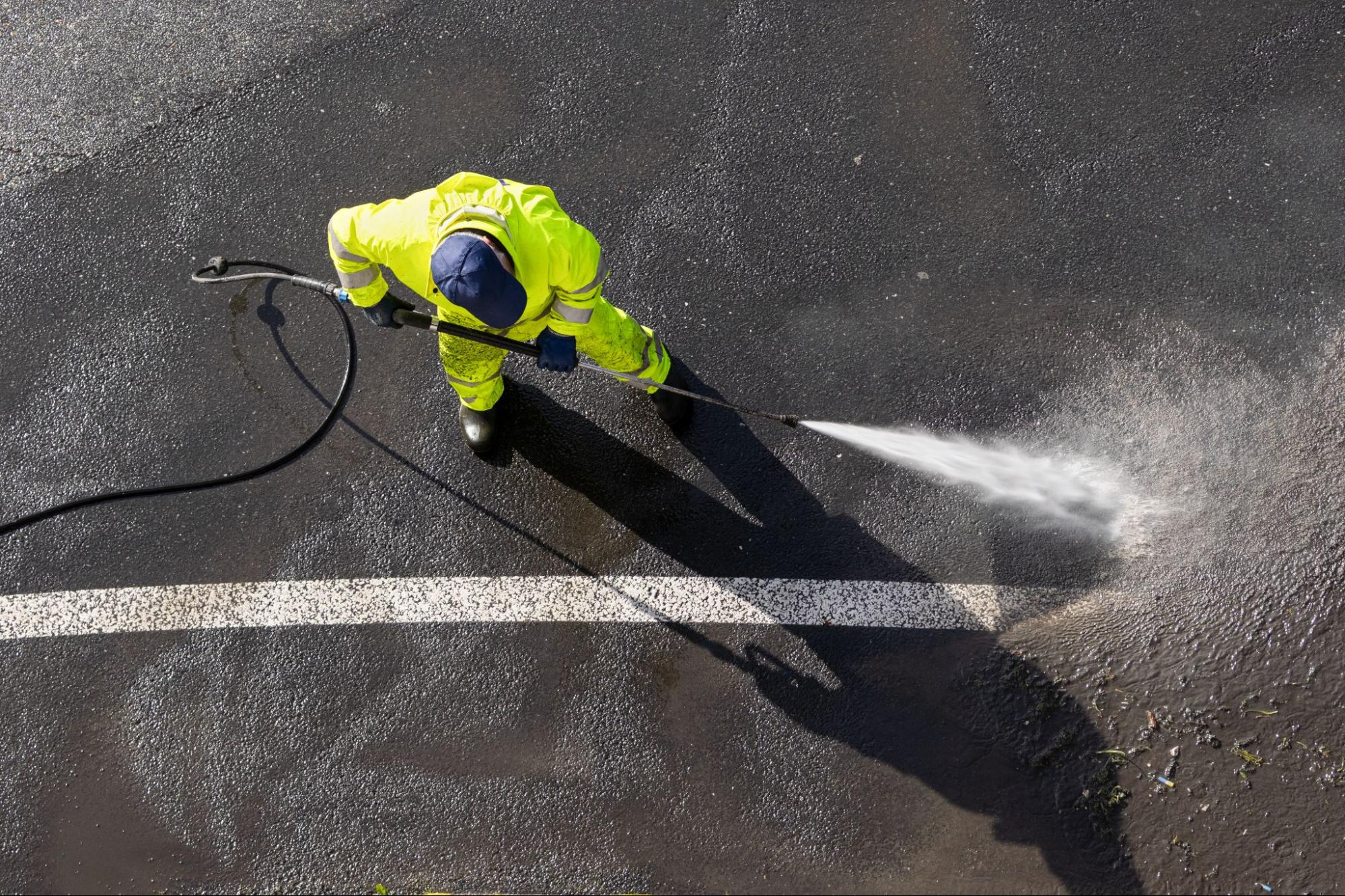 An overview of a worker power washing a parking lot.