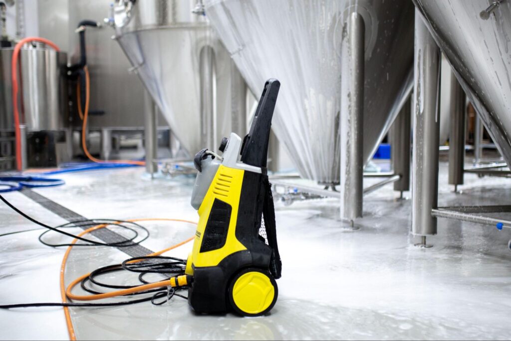 A black and yellow high-pressure washing equipment resting on a warehouse floor