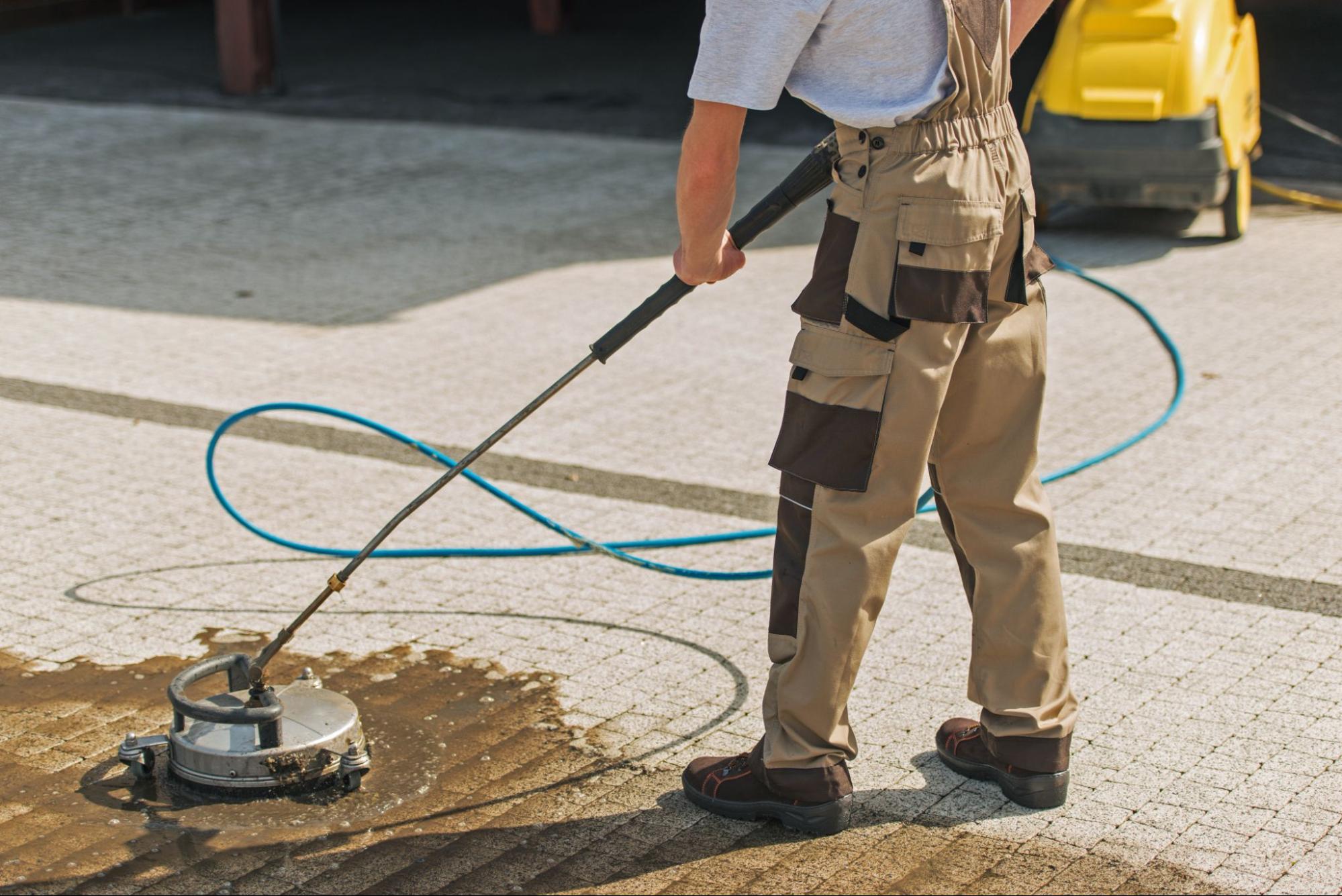 Cropped view of a worker cleaning a home driveway using a pressure washer