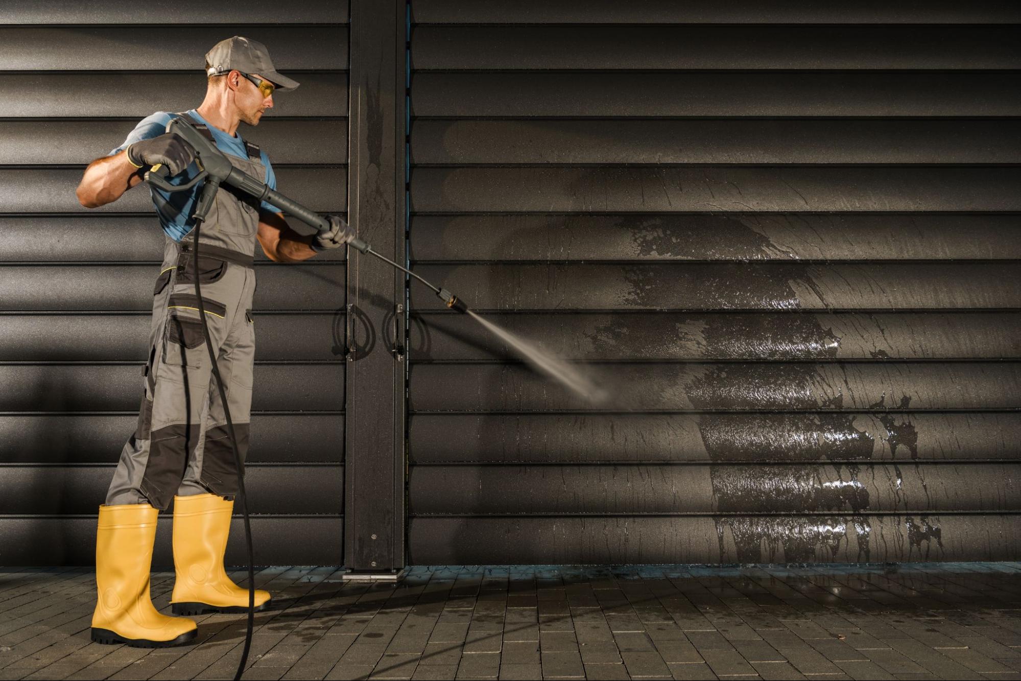 Cleaner using a commercial pressure washer on a modern aluminum pergola
