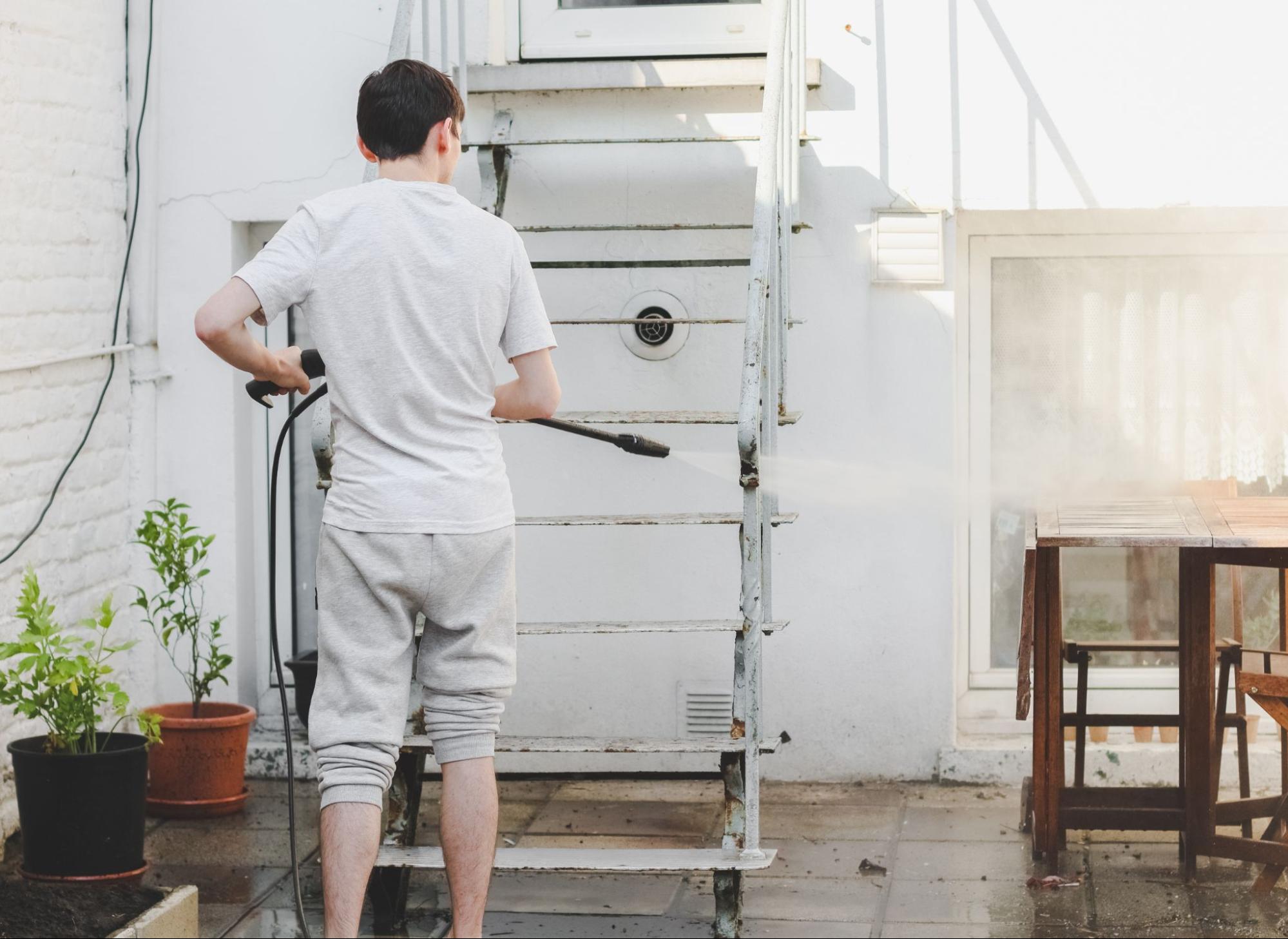 A DIYer cleans his front stairs with a pressure washer.