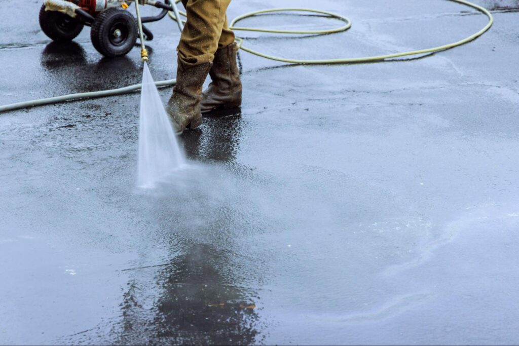 Close-up of a professional cleaner using a pressure washer to clean parking lot floors