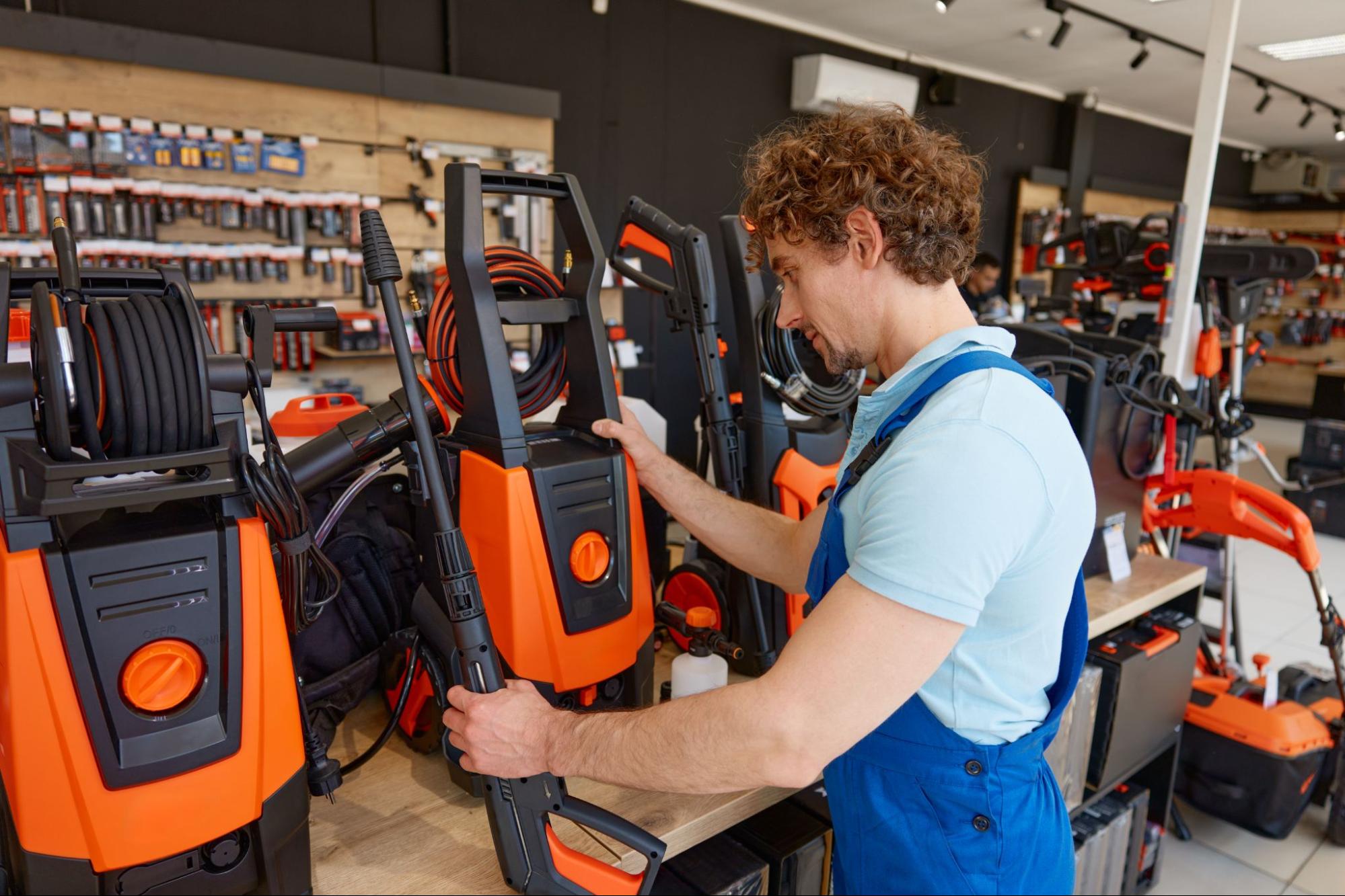 A man selecting a commercial pressure washer at a hardware store